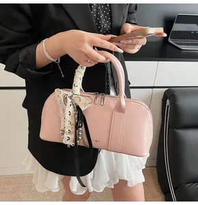 Detalle de bolso Boston rosa con lazos de encaje y adornos plateados finos
