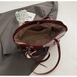 Top view of dark red tote bag showing brown lining, inner zipper pocket and magnetic closure