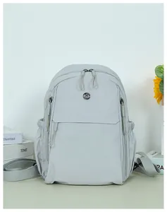 Detail view of a light gray waterproof nylon backpack with metal logo and side zipper