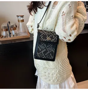 Detail of elegant black crossbody phone bag with gold clover lock and pattern embroidery