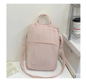 Detail of light pink wrinkled texture nylon bag with zipper front pocket on desk