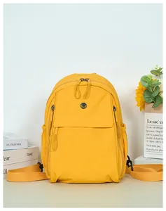 Detail view of the yellow backpack with multiple zipper pockets and a side elastic pouch