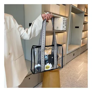 Close-up of a clear PVC tote bag with black trim and a wide jacquard patterned strap