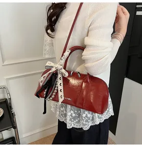 Detalle de bolso cilíndrico rojo brillante con cinta de encaje y cadena de plata fina