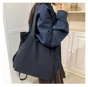 Detail van de trekkoordsluiting aan de zijkant van een grote zwarte nylon shopper