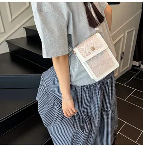 Detail of white cross body bag with embroidery and gold clover buckle on a model