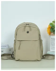 Detail of a khaki nylon backpack showing the front hidden zipper pocket and metal logo