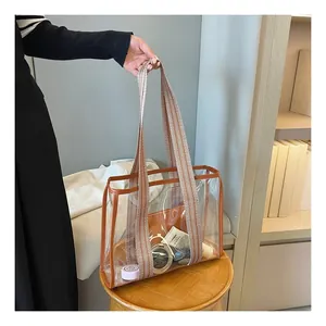 Macro detail of clear PVC tote bag with brown leather trim and geometric wide strap