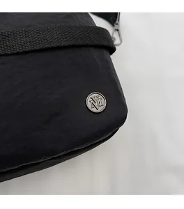 Detail of black wrinkled nylon fabric with silver metal logo and strap hardware