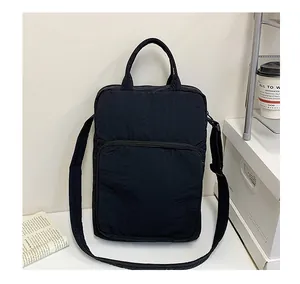 Detailed view of black nylon messenger bag with large front zipper pocket on white desk