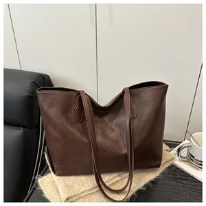 Detail view of deep brown faux leather tote bag with a smooth vintage texture and slim strap