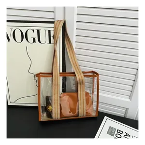 Detail of transparent PVC tote bag with brown leather trim and wide striped woven strap