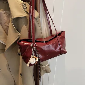 Minimalist deep red oil wax leather underarm tote bag with a baseball charm and shoulder straps