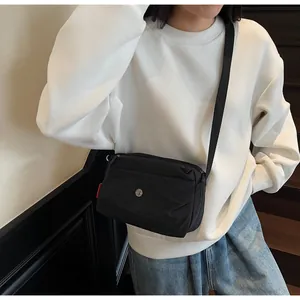 Modell mit minimalistischer schwarzer Nylon-Umhängetasche mit verstellbarem Riemen und Logo