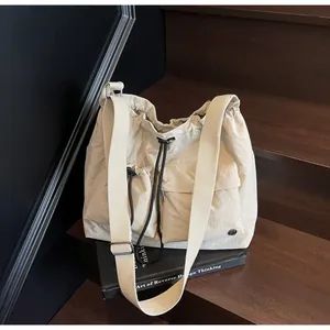 Detail of beige nylon crossbody bag with drawstring closure and large flap pockets
