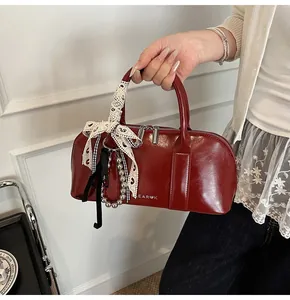 Primer plano del bolso bowling rojo brillante con lazos de encaje y adornos de perlas
