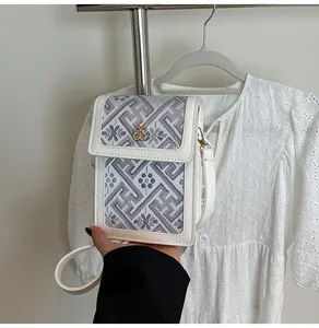 Close-up of floral embroidery on a white leather mini bag with clover metal clasp