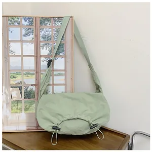 Dettaglio borsa hobo verde chiaro con base a coulisse su tavolo in legno