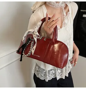 Detalle del bolso de hombro en cuero brillante burdeos con logo clear k y lazo encaje