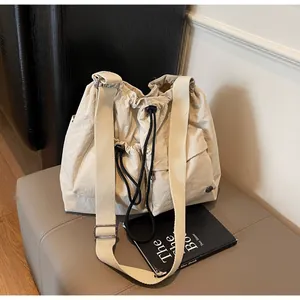 Detail view of large nylon drawstring crossbody bag with textured fabric and wide strap