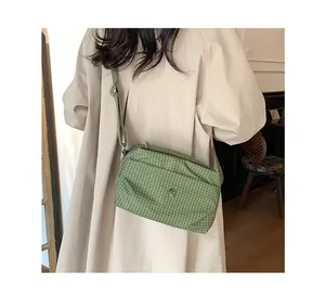 Détail du sac bandoulière en toile à carreaux verts avec sangle réglable sur modèle