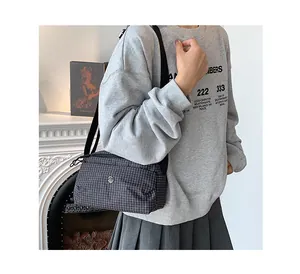 Sac bandoulière en toile à carreaux foncés avec large sangle et logo en métal rond