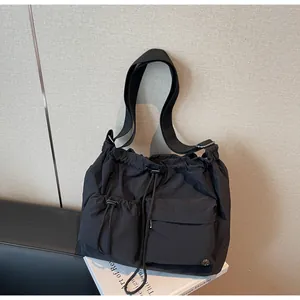Detail of high-density black nylon cargo bag showing drawstring pockets and metallic logo