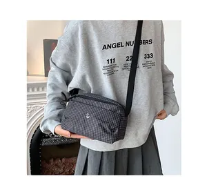 Vue détaillée d'un sac bandoulière à carreaux avec logo rond et sangle noire