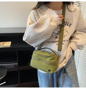Detail view of the green nylon crossbody bag showing dual zippers and texture