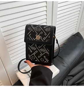 Detailed embroidery and gold four-leaf clover metal buckle on the black mini square bag