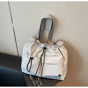 Detailed close-up of light gray nylon crossbody bag with drawstring pockets and metal buckle