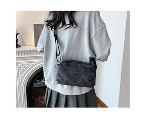 Détail d'un sac bandoulière à carreaux avec sangle ajustable et numéro 32 porté