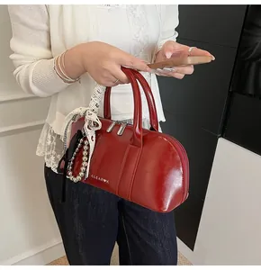 Detalle de bolso de hombro en charol rojo con pañuelo de seda y colgante de cuentas