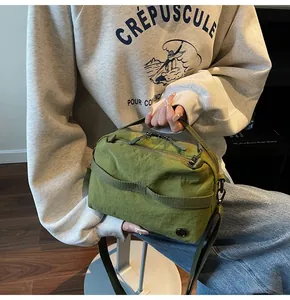 Detailed macro view of olive green nylon crossbody bag showing crinkled texture and metal logo