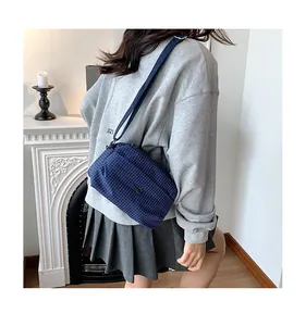 Détail d'un sac bandoulière en toile à carreaux bleus porté avec une tenue décontractée