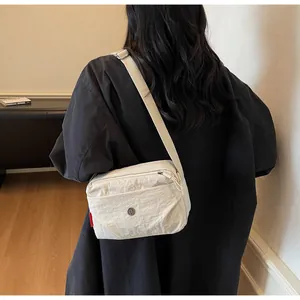 Detail der beigen Nylon-Umhängetasche mit verstellbarem Gurt und vorderem Reißverschlussfach