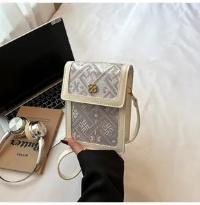 Close-up of floral embroidery detail and gold clover clasp on beige crossbody phone bag