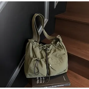 Detail view of military green nylon crossbody bag with dual pockets on wooden steps