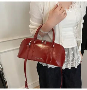 Detalle del bolso Boston de charol rojo con logotipo plateado y correa ajustable
