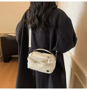 Detail of minimalist cream nylon crossbody bag with adjustable strap and zip closure
