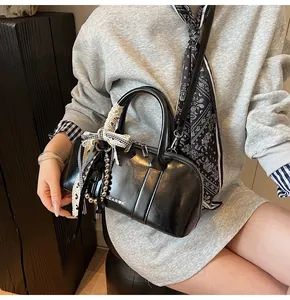 Detalle de bolso Boston de cuero negro con cadena de perlas y logotipo blanco impreso