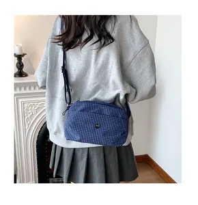Détail d'un sac bandoulière en toile à carreaux bleu marine porté par un mannequin
