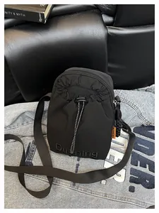 Détail du sac bandoulière en nylon noir avec poche à cordon et étiquette orange
