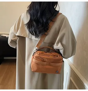Caramel brown crossbody bag detail showing textile texture and metal logo plaque