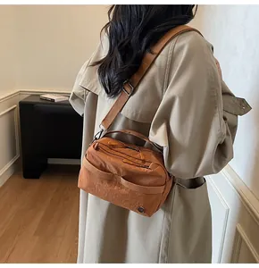 Close-up of brown nylon crossbody bag with wide adjustable strap and metal hardware