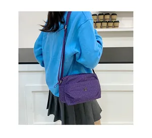 Détail du sac bandoulière en toile à carreaux violet avec sangle réglable et logo