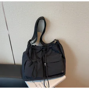 Macro view of black nylon pleated shoulder bag showing drawstring closure and side pockets