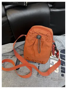 Détail du sac bandoulière orange en nylon avec poche à cordon et sangle réglable