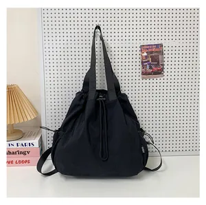 Detail van zwarte nylon emmer-tas met trekkoord, geweven label en brede schouderband