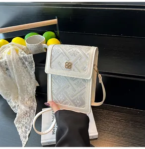 Close-up of cream crossbody bag with gold floral embroidery and clover clasp details